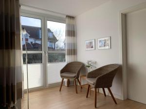 2 stoelen en een tafel in een kamer met ramen bij Ferienwohnung Ostseeglück in Boltenhagen