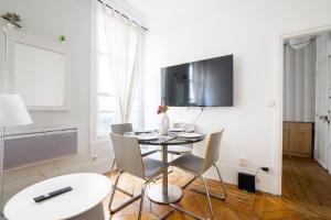 uma sala de jantar com mesa e cadeiras e uma televisão em Appartement Quartier Musée du Louvre Free Netflix em Paris