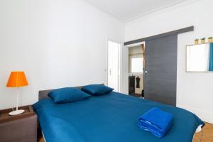uma cama azul com almofadas azuis num quarto em Appartement Quartier Musée du Louvre Free Netflix em Paris