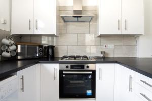 a kitchen with white cabinets and a stove top oven at Spacious 4-Bedroom Apt | Pool Table in Cardiff