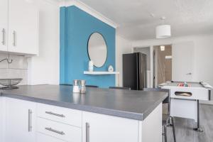 a kitchen with white cabinets and a blue wall at Spacious 4-Bedroom Apt | Pool Table in Cardiff +44 photos