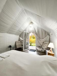 a bedroom with a white bed and two chairs at PINIALE GLAMPING TRIB in Bughea de Jos