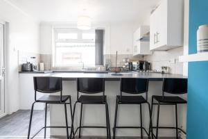 a kitchen with a large counter with four bar stools at Spacious 4-Bedroom Apt | Pool Table in Cardiff