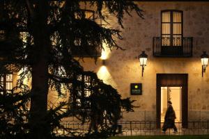 a woman walks in front of a building at night at Eunice Hotel Gastronómico in Salamanca