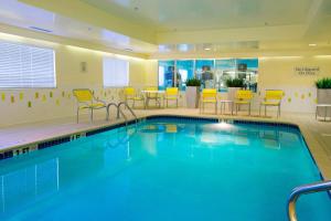 una piscina en una habitación de hotel con sillas y mesas en Fairfield Inn Huntsville, en Huntsville