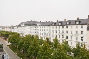 コペンハーゲンにあるホテル サンクト エニーの目の前に木々が植えられた白い大きな建物