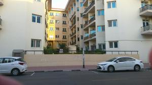 dos autos blancos estacionados en un estacionamiento al lado de un edificio en Ruby Star Hostel Loft Bed 21 en Dubái