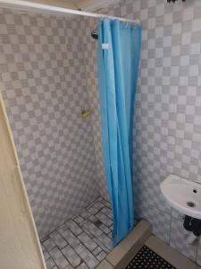 eine Dusche mit blauem Vorhang neben einem Waschbecken in der Unterkunft BERG STREET APARTMENTS in Johannesburg