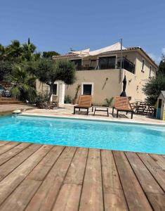 a swimming pool with two benches and a house at Villa 6 personnes avec grande piscine - 5 min des plages in Fréjus