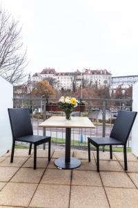2 sillas y una mesa con un jarrón de flores en el balcón en Apartmány U zámku en Český Krumlov