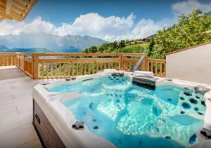 a hot tub on a deck with mountains in the background at Chalet Nougat - Les Congères in Manigod