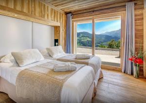 two beds in a room with a large window at Chalet Nougat - Les Congères in Manigod