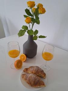 a table with two glasses of orange juice and a vase with flowers at Apartman Melita in Galižana