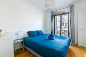a blue bed in a room with a window at Appartement Quartier la Madeleine Free Netflix in Paris