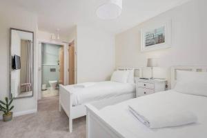 a white bedroom with two beds and a mirror at Argyle Rigg * Deluxe Central Townhouse * Balcony in St Andrews