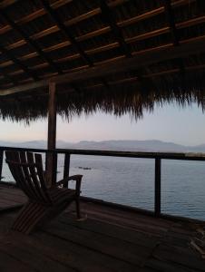 um banco sentado sob uma cabana de palha ao lado da água em Club Cadena em Acapulco