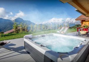 a hot tub on a patio with a view of a mountain at Chalet Chamallow - Les Congères in Manigod