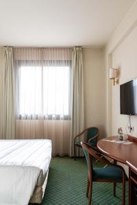 a hotel room with a bed and a desk and a table at Phi Hotel Emilia in Ozzano dell'Emilia