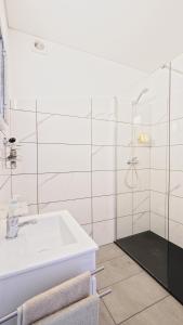 a white bathroom with a sink and a shower at Guest House Dianamar in Albufeira