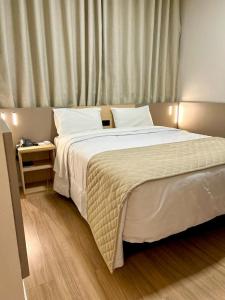 sypialnia z dużym białym łóżkiem i stolikiem w obiekcie Hotel Alji w mieście Indaiatuba