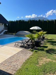 a pool with tables and umbrellas next to a house at IV Gemütliche Ferienwohnung in Pool-Position in Sankt Michael ob Bleiburg