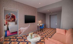 a living room with a couch and a tv in a room at NH Collection Roma Vittorio Veneto in Rome