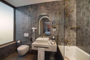 a bathroom with a sink and a toilet and a tub at NH Collection Roma Vittorio Veneto in Rome