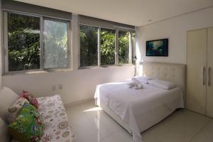 ein weißes Schlafzimmer mit einem Bett und Fenstern in der Unterkunft Rio Spot Leblon D049 in Rio de Janeiro