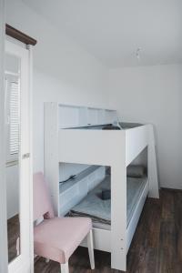 un letto a castello bianco con una sedia rosa in una stanza di Villa Sabrina a Klimno