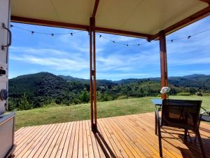 a porch with a table and a view of the mountains at Trailer na montanha próximo de Monte Verde in Camanducaia