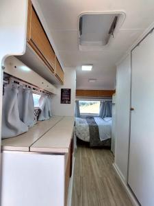 uma cozinha e um quarto num trailer com uma cama em Trailer na montanha próximo de Monte Verde em Camanducaia