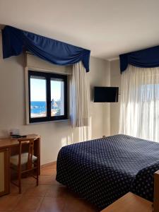 1 dormitorio con cama, escritorio y ventana en Hotel Lachea, en Aci Trezza