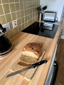 a loaf of bread on a cutting board with a knife at Charming, Cozy Apartment, 2 mins from the Beach in Llanfairfechan