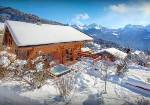 a log cabin in the snow with mountains at Chalet Guimauve - Les Congères in Manigod