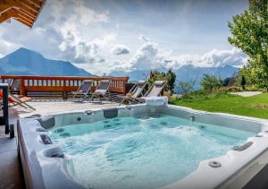 einen Whirlpool auf einer Terrasse mit Stühlen und Bergen in der Unterkunft Chalet Guimauve - Les Congères in Manigod