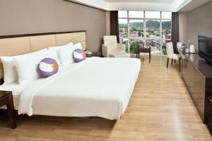 a bedroom with a large white bed and a desk at FOX Hotel Gorontalo in Gorontalo