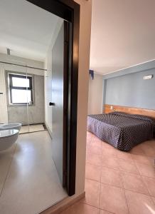 a bedroom with a bed and a bathroom at Hotel Lachea in Acitrezza