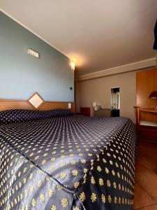 a bedroom with a bed with a blue and white comforter at Hotel Lachea in Acitrezza