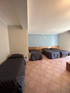 a room with three beds and a tiled floor at Hotel Lachea in Acitrezza