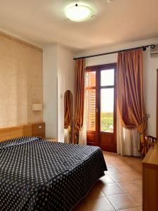 a bedroom with a bed and a large window at Hotel Lachea in Acitrezza