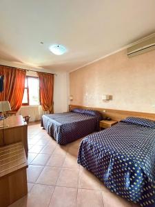 a hotel room with two beds and a desk at Hotel Lachea in Acitrezza