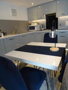 cocina con mesa blanca y 2 sillas azules en Ty Ni Holiday Apartment Aberdovey en Aberdyfi