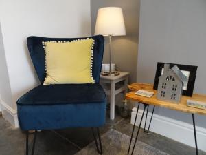 a blue chair with a yellow pillow next to a table at Ty Ni Holiday Apartment Aberdovey in Aberdyfi