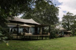 a house with a tent in the grass at Zambezi Sands by Batoka in Victoria Falls