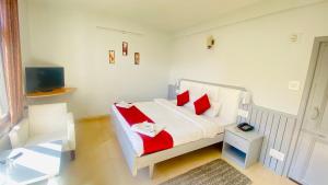 a bedroom with a white bed with red pillows at Hotel Himalayan Meadows in Manāli