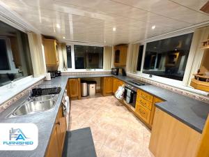 a kitchen with wooden cabinets and a sink and windows at Large House - Relocation - Families in Manchester