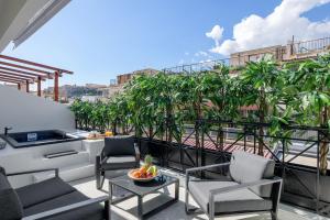 einen Balkon mit Stühlen, einem Tisch und Palmen in der Unterkunft Penthouse W/ View & Plunge Pool in Athen