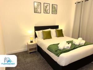 sypialnia z łóżkiem z zielonymi i białymi poduszkami w obiekcie Large House - Relocation - Families w Manchesterze