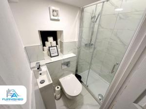 a bathroom with a toilet and a glass shower at Large House - Relocation - Families in Manchester