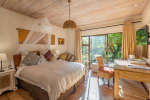 a bedroom with a large bed and a desk and a window at Tidal Retreat in Plettenberg Bay